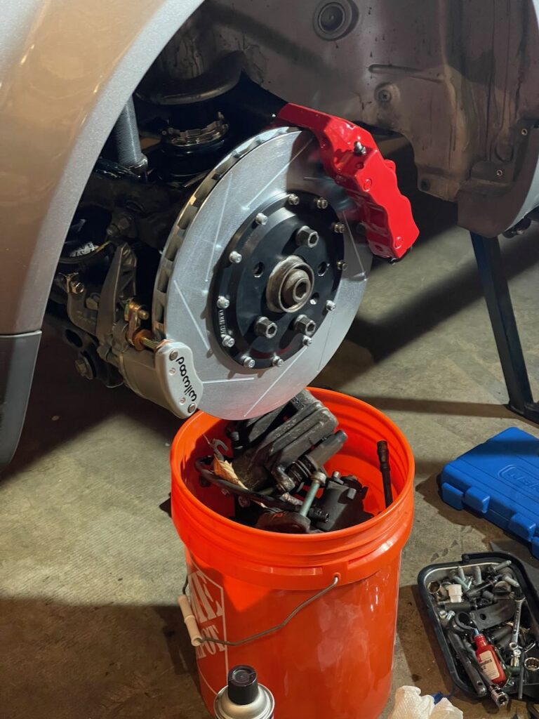 Red brake caliper and slotted rotor.
